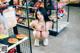 A woman sitting on the floor in front of a shelf of food.