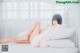 A woman laying on top of a bed covered in fluffy white pillows.