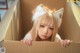 A woman in a cardboard box with a cat ears headband.