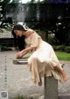 A woman in a white dress sitting on a bench.