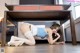 A woman laying on the floor under a desk.