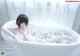 A woman sitting in a bathtub filled with white balls.