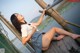 A woman in a school uniform is sitting on a wooden dock.