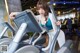 A woman in a blue top and white pants on a treadmill.